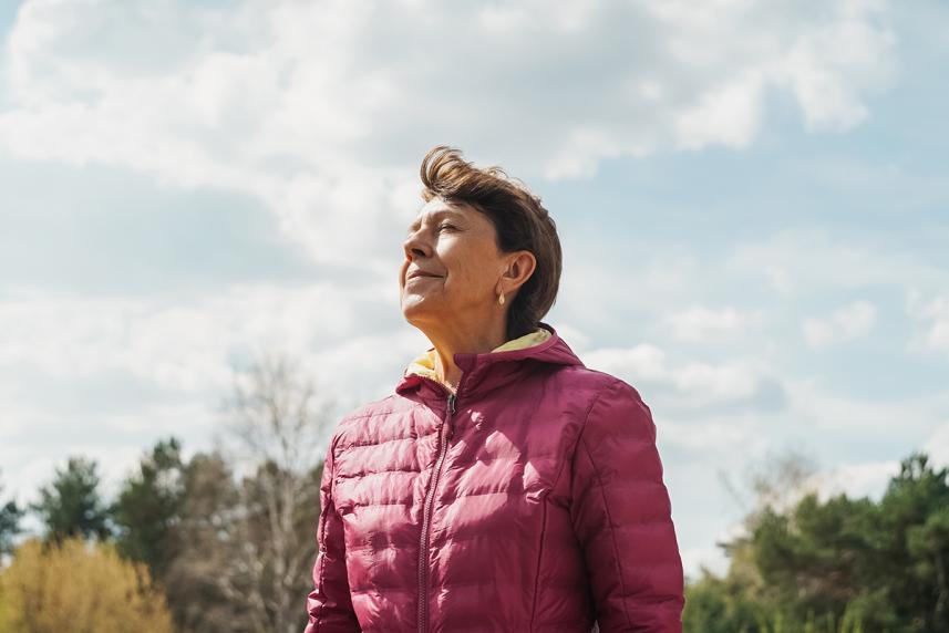 A woman closing her eyes, breathing in nature