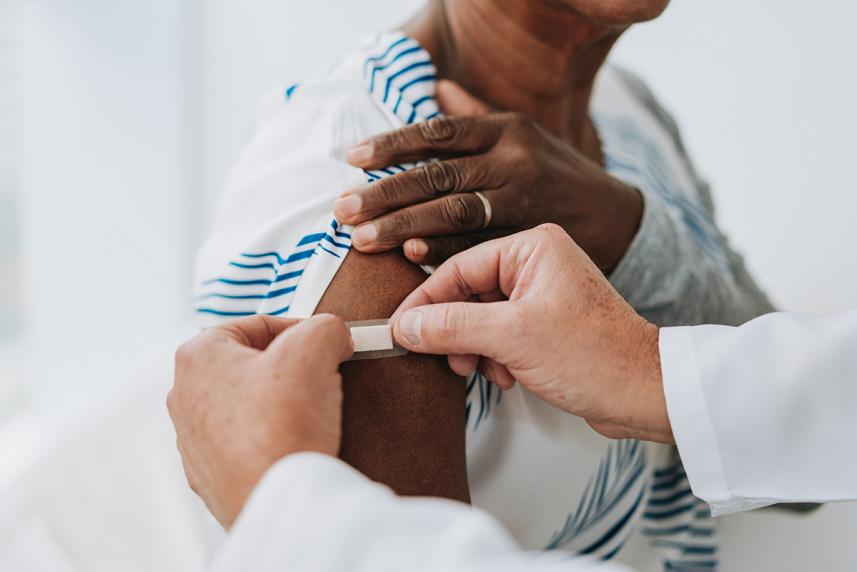 Close up of a healthcare professional putting a bandaid on a patients arm