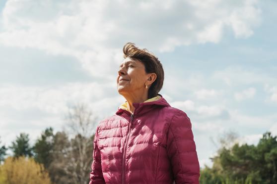 A woman closing her eyes, breathing in nature