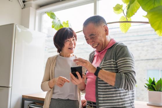 A couple smiling, looking at a smartphone