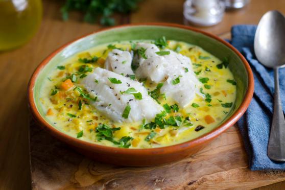 Photo: Bowl of creamy fish and chive chowder, with rustic table setting.